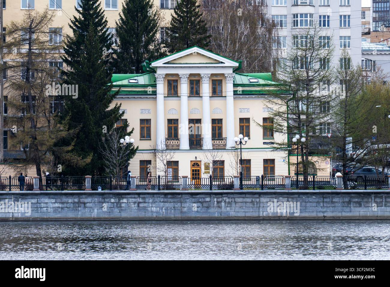 Edificio storico con architettura classica e tetto verde sul lungofiume, circondato da alberi e ambiente urbano, che presenta un design elegante e un Foto Stock