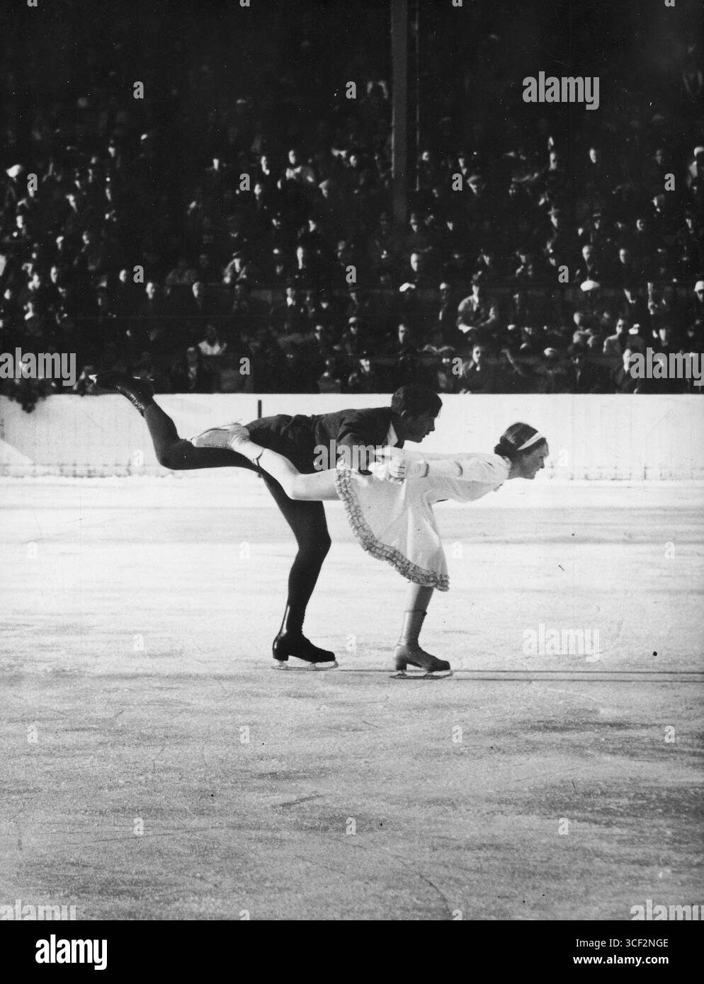 Ilse Pausin e Erik Pausin gareggiano nell'evento di pattinaggio di figura a coppie alle Olimpiadi invernali del 1936, eseguendo una spirale. La loro routine era segnata dalla grazia e dall'abilità tecnica. Foto Stock