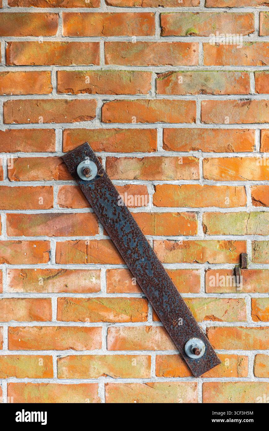 Muro in mattoni, vecchio muro in pietra con piastra di rinforzo arrugginita. Foto Stock