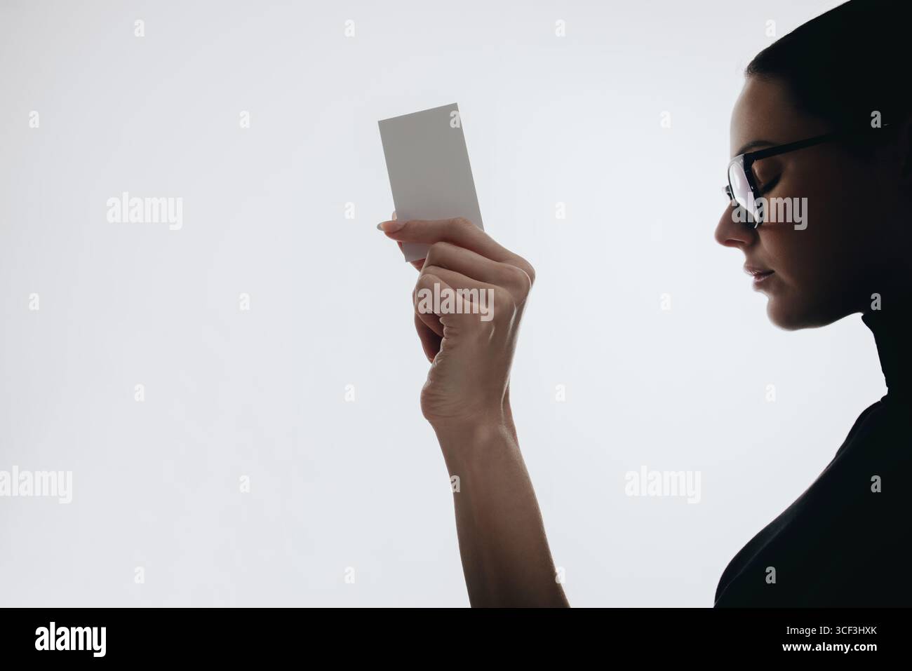 Vista laterale di una donna professionista con un biglietto da visita vuoto, su sfondo bianco. Ideale per modelli di biglietti da visita, presentazioni di branding, aziende Foto Stock