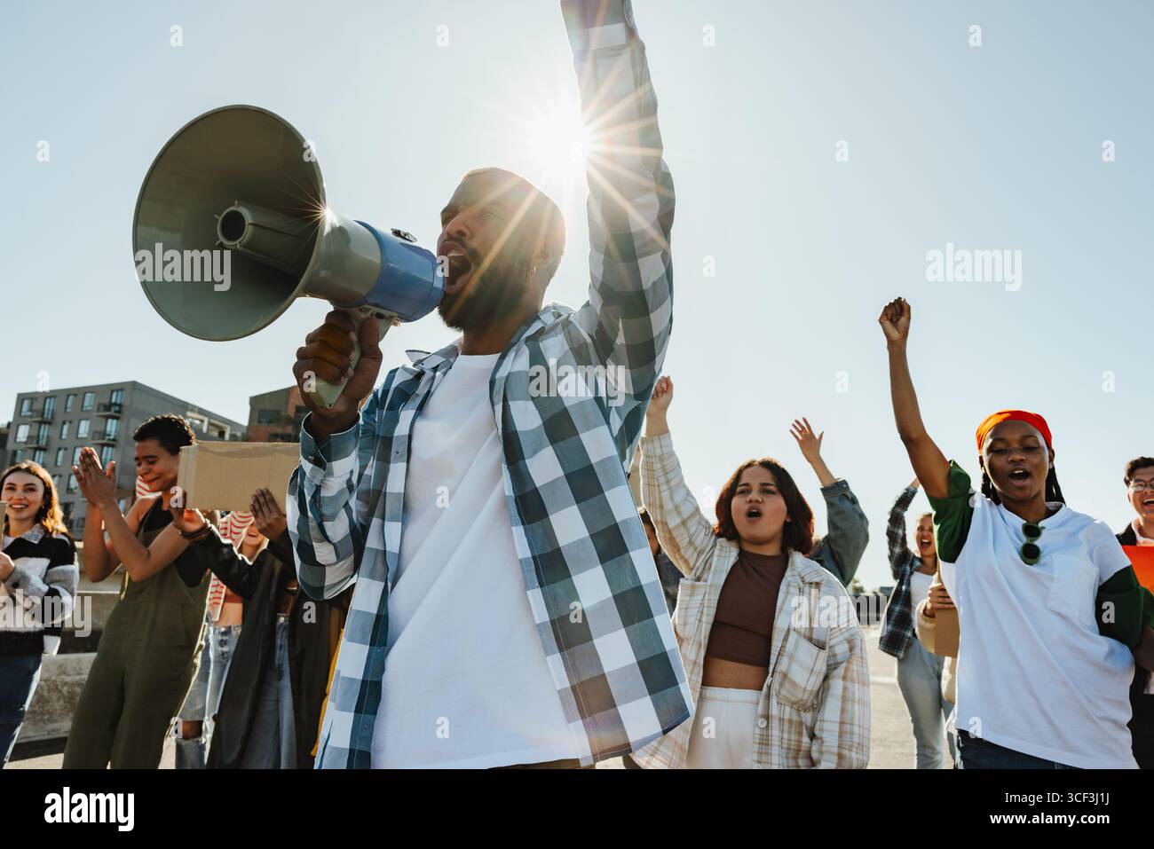 Un determinato gruppo di individui, sia uomini che donne di varie età, protestano appassionatamente all'aperto alla luce del sole, tenendo dei cartelli e focalizzandosi su un Foto Stock
