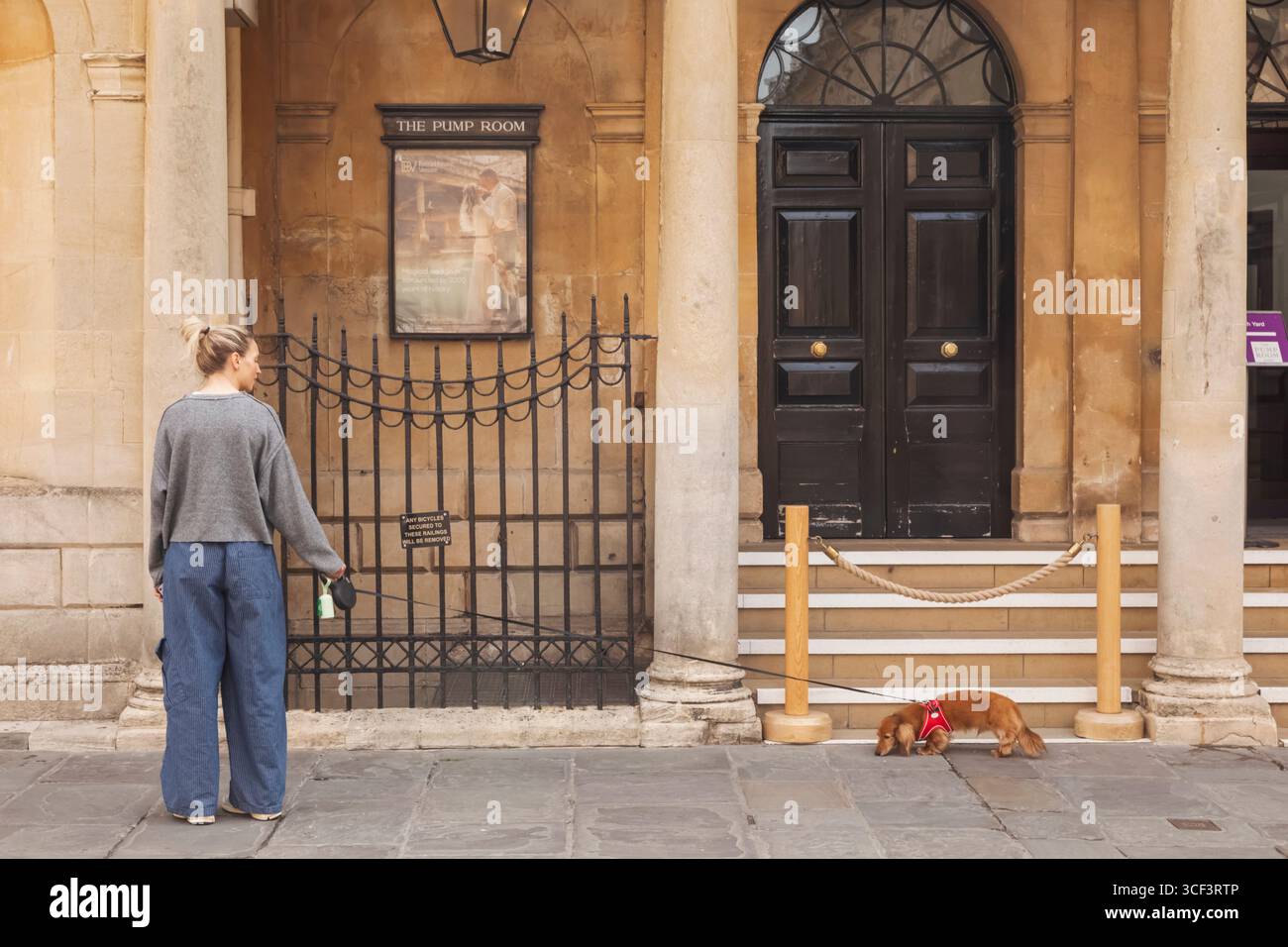 Inghilterra, Somerset, Bath, donna con cane davanti alla sala pompe Foto Stock
