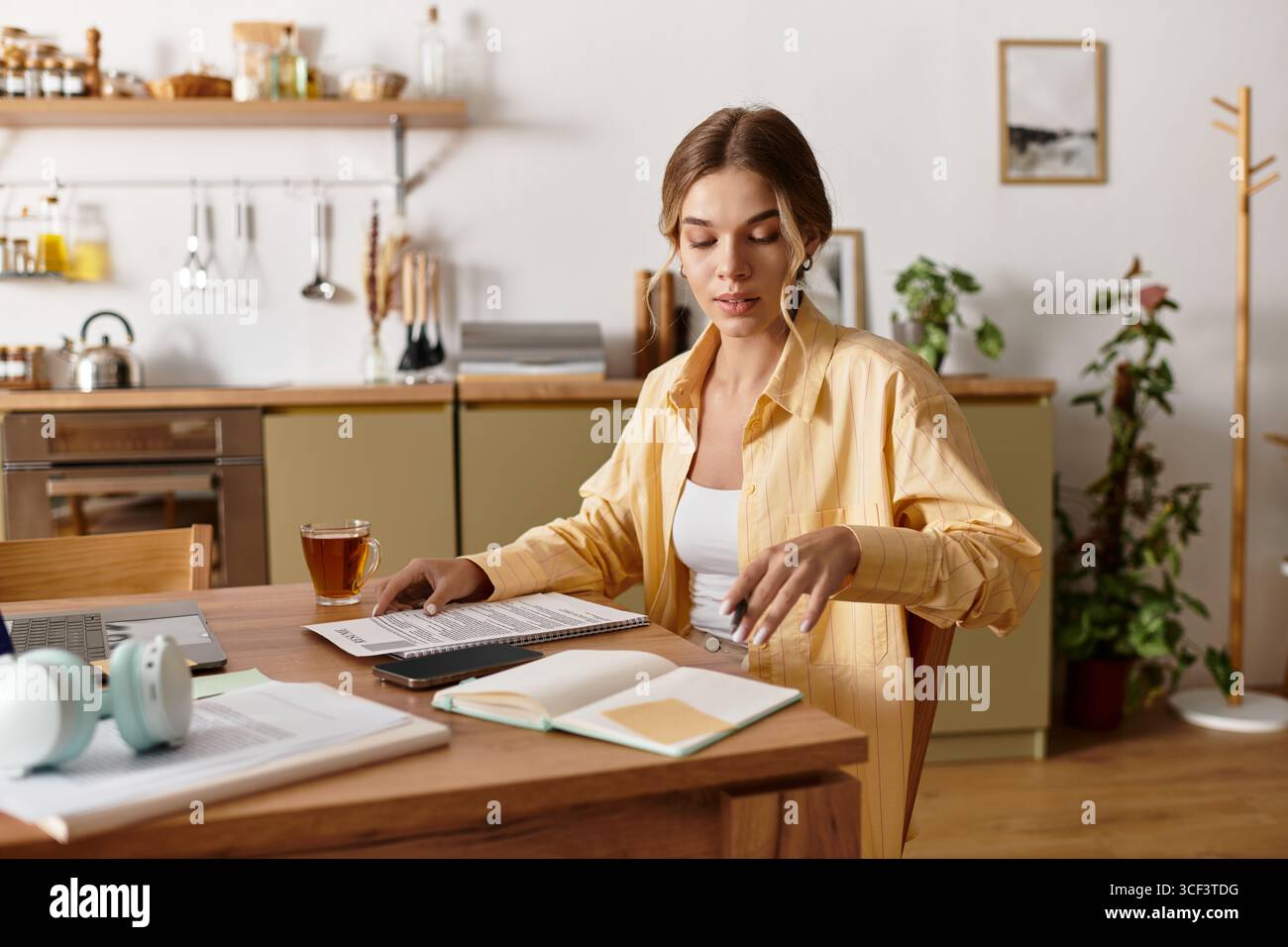 Spazio luminoso e invitante dove una giovane donna si impegna a lavorare con cura sorseggiando un tè. Foto Stock