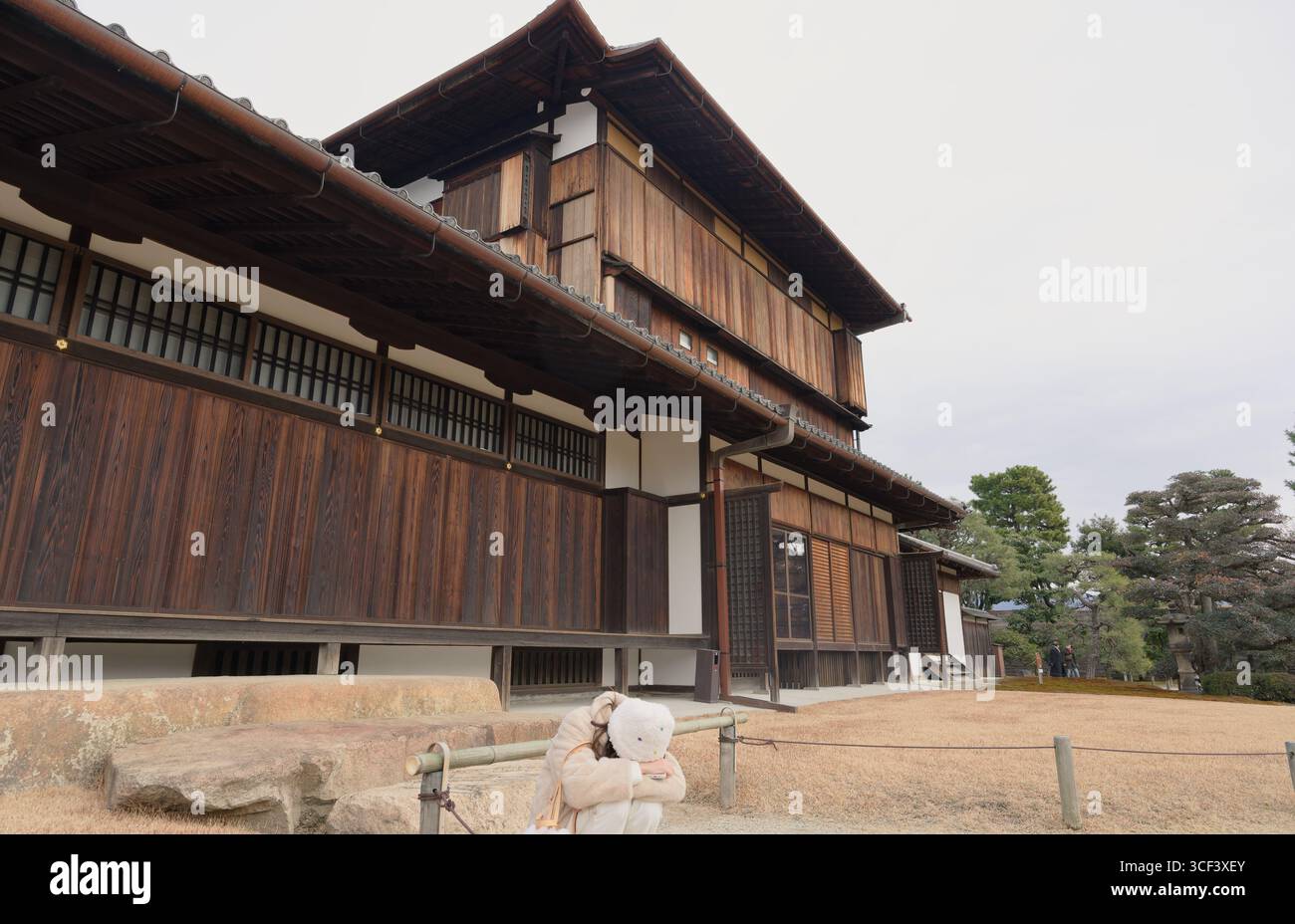 Momento di solitudine mentre una giovane donna si siede avvolto all'esterno delle sale di legno del Castello Nijo a Kyoto Foto Stock