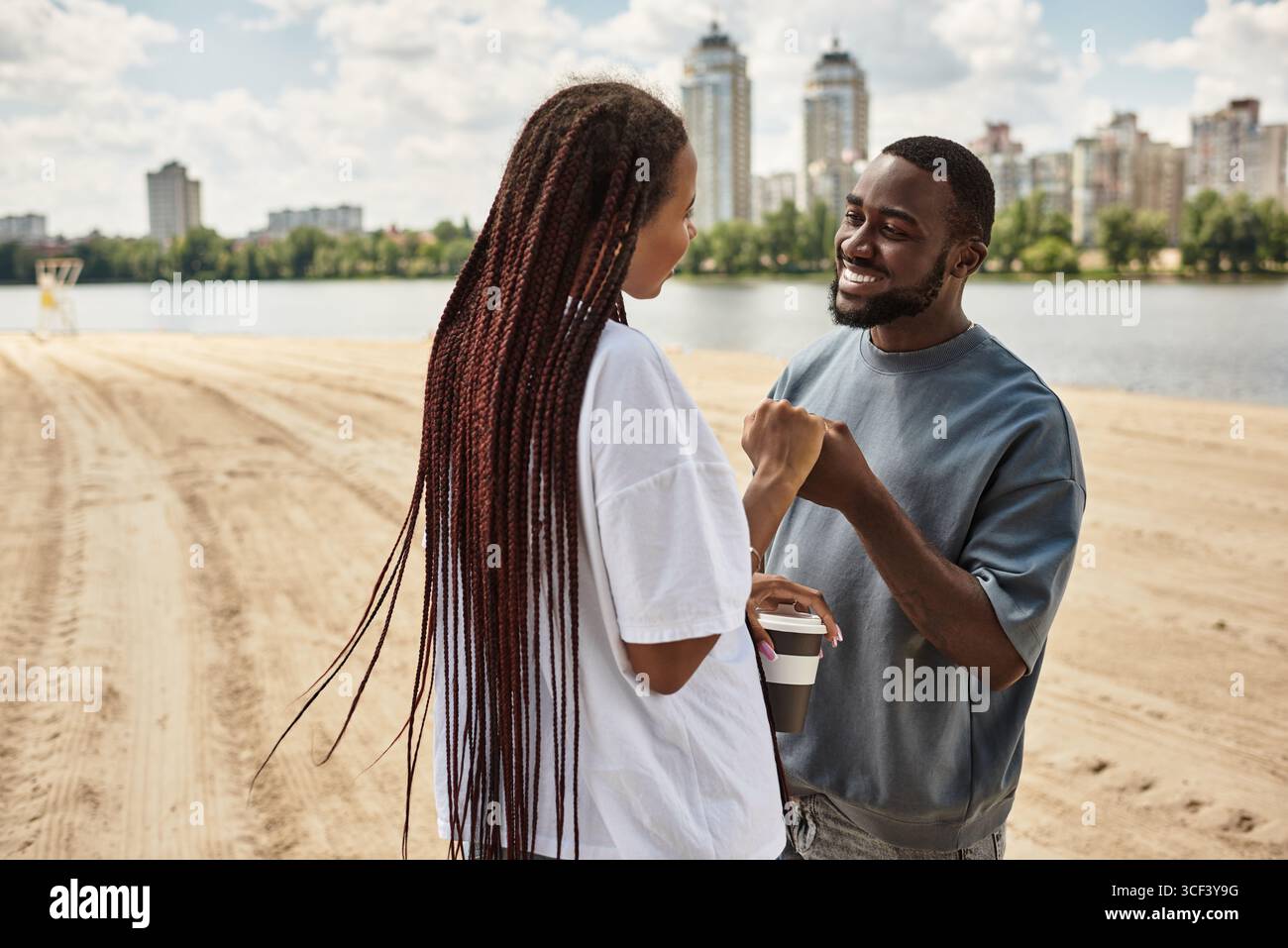 Una giovane coppia gode di un momento di gioia passeggiando lungo il fiume, abbracciando l'amore. Foto Stock
