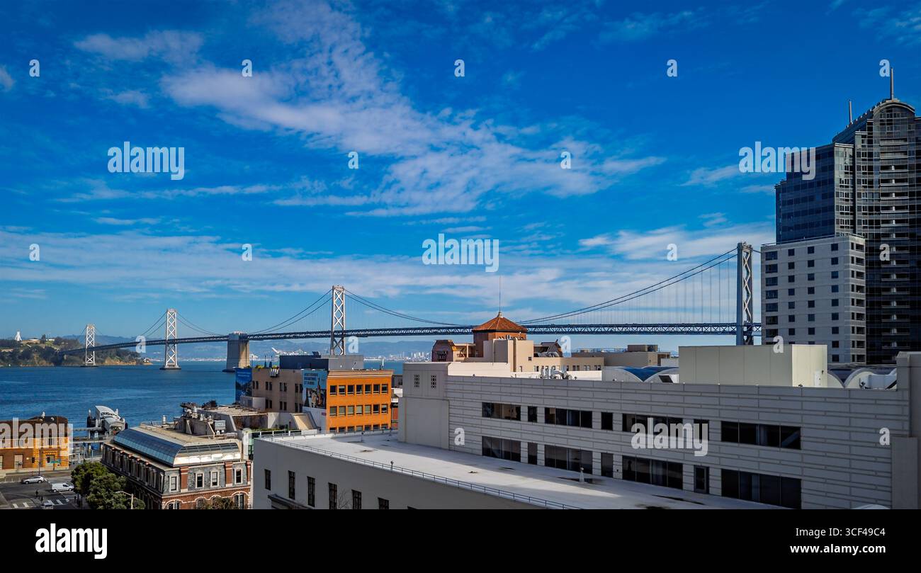 Il San Francisco Oakland Bay Bridge attraversa la baia con un paesaggio urbano e edifici in una giornata di sole limpido a San Francisco, Stati Uniti Foto Stock