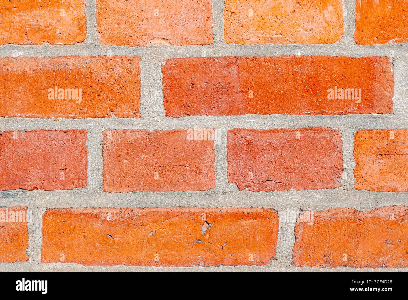 Una vista dettagliata di una classica parete in mattoni rossi, che mette in risalto i toni caldi, le texture ruvide e il ritmo strutturato della muratura. Foto Stock