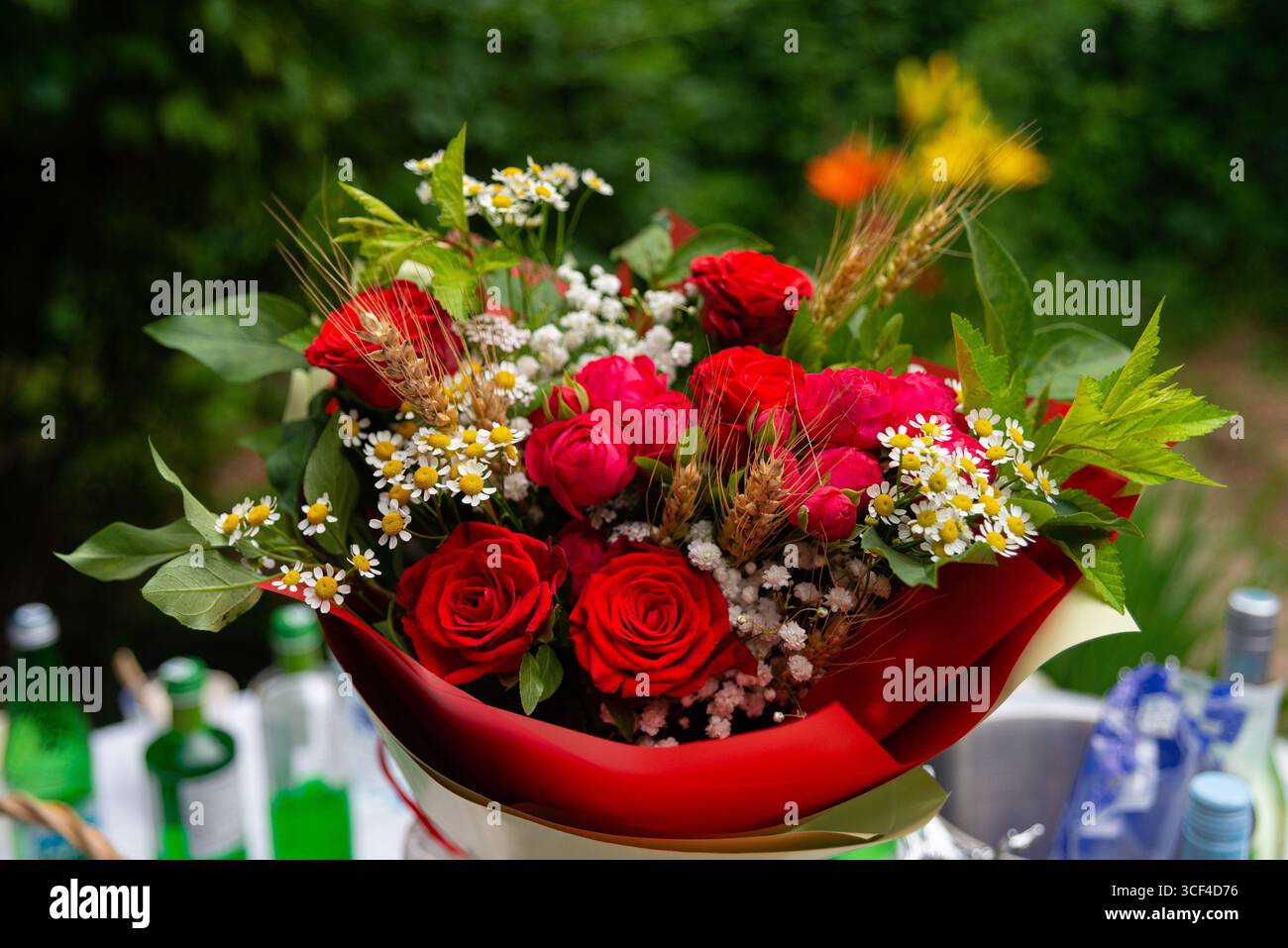 Un bellissimo e vibrante bouquet caratterizzato da rose rosse e fiori bianchi. la vegetazione lussureggiante e le delicate fioriture creano una perfetta disposizione, ideale per le celebrità Foto Stock