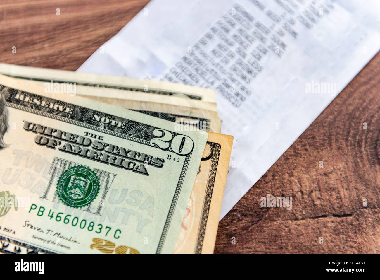 Un mucchio di banconote da dollari americani su un supermercato fino alla ricevuta su un tavolo. Un concetto del costo della vita negli Stati Uniti. Foto Stock