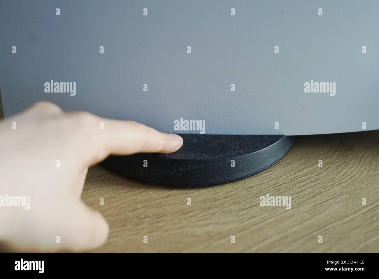 Toccare la base di un monitor moderno su una scrivania in legno per la pulizia della polvere Foto Stock