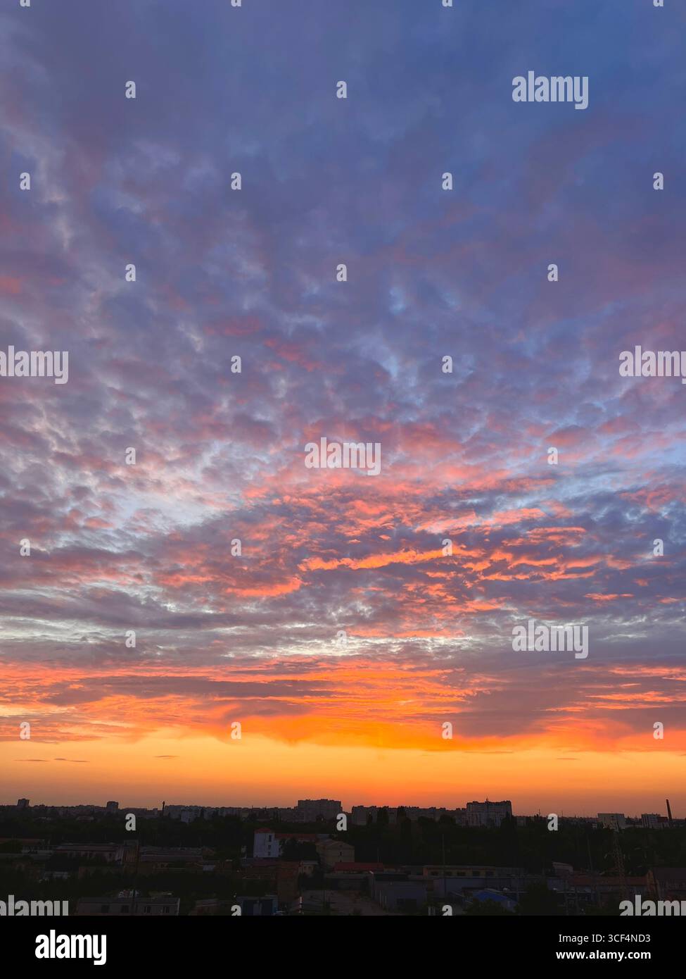 tramonto arancione con nuvole grigio lilla, tramonto sulla città Foto Stock
