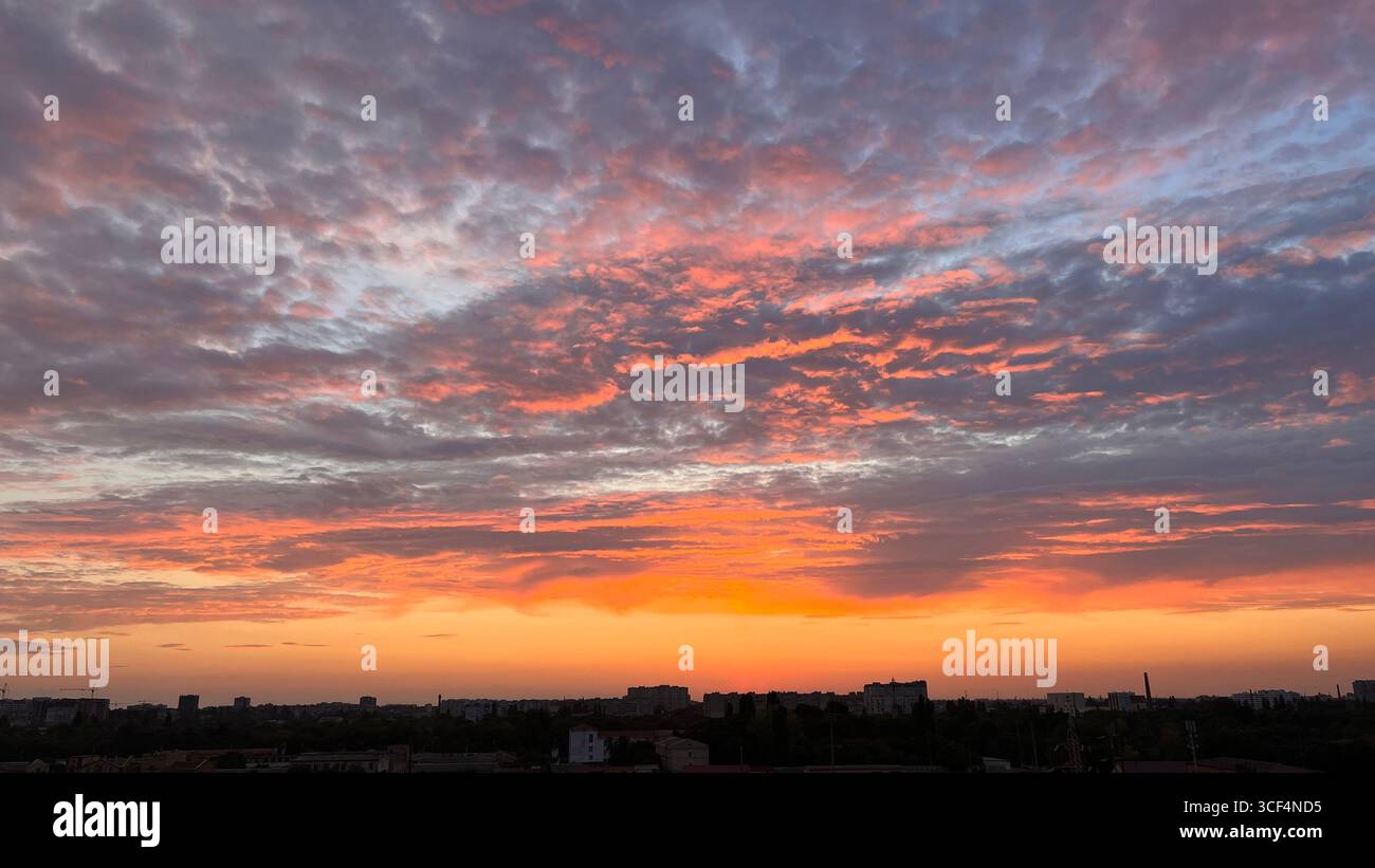 tramonto arancione con nuvole grigio lilla, tramonto sulla città Foto Stock