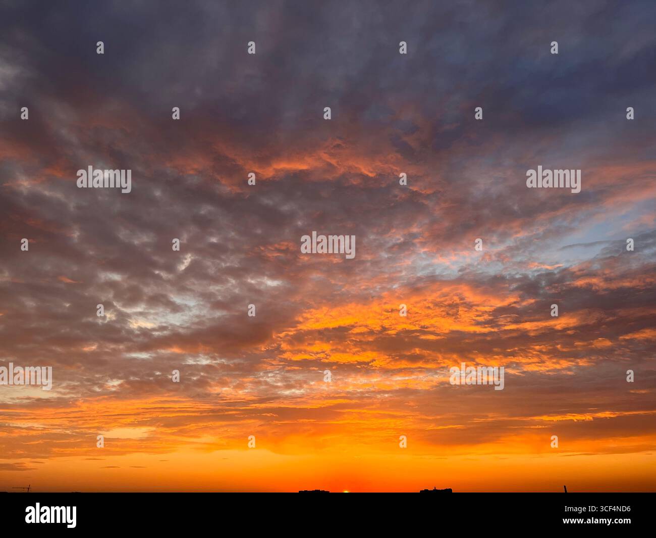tramonto arancione con nuvole grigio lilla, tramonto sulla città Foto Stock