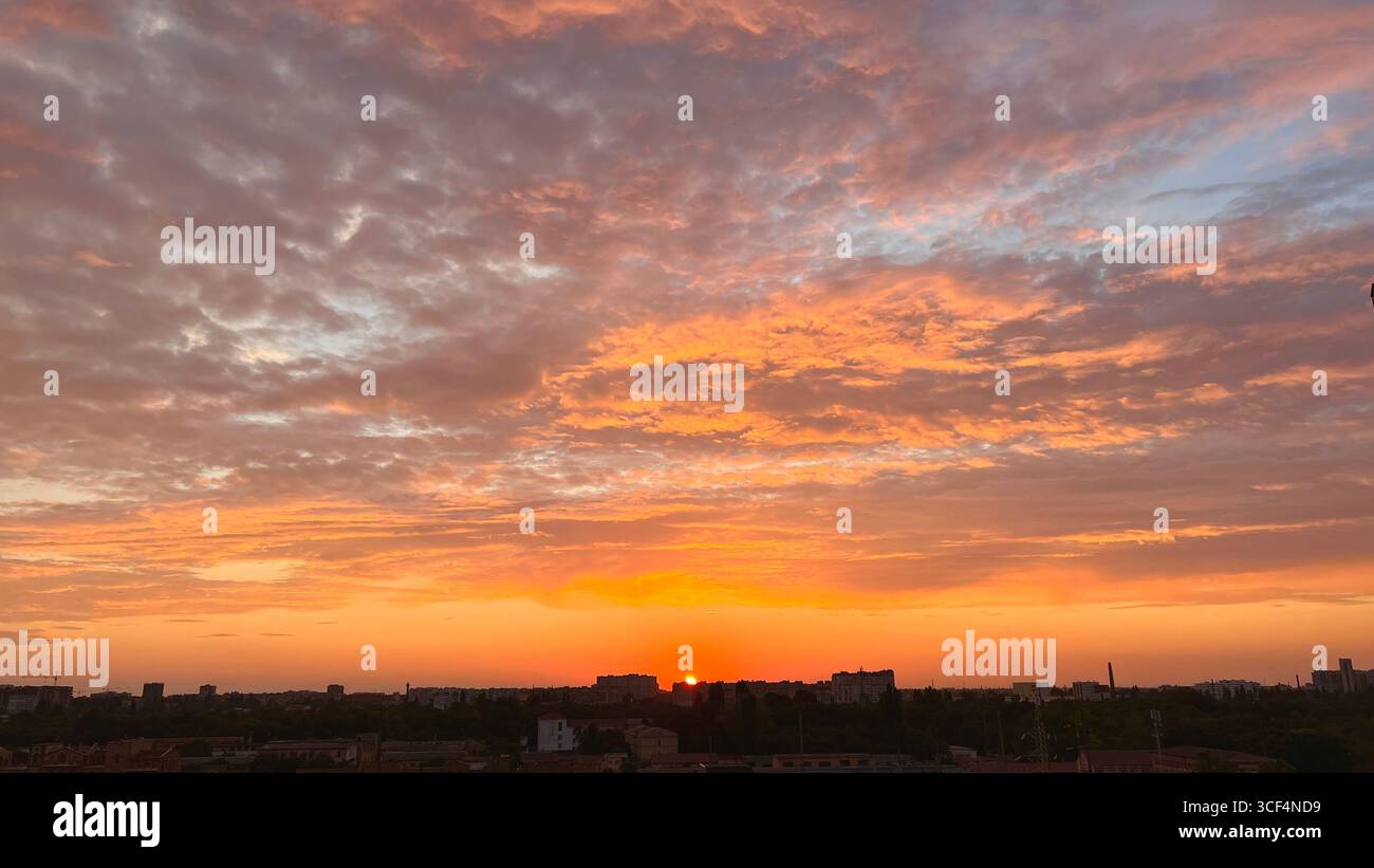 tramonto arancione con nuvole grigio lilla, tramonto sulla città Foto Stock