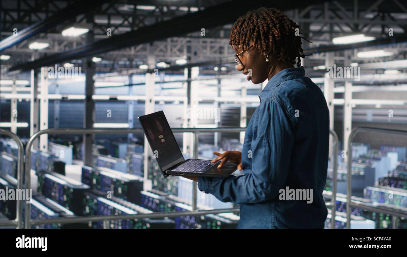 Lo sviluppatore di software per data center si prende il panico dopo aver ricevuto un messaggio di errore critico sul display del notebook. Donna afroamericana nell'hub server avvisata da bug che causano basse prestazioni hardware Foto Stock