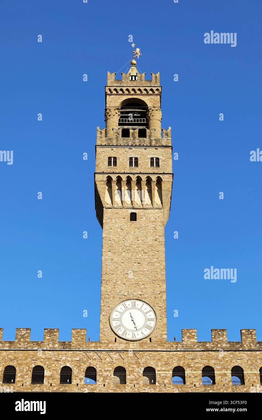 L'imponente Torre di Palazzo Vecchio si erge su di un cielo blu vibrante e mostra la sua intricata architettura e l'orologio storico, un simbolo del ricco patrimonio di Firenze e della sua bellezza senza tempo Foto Stock