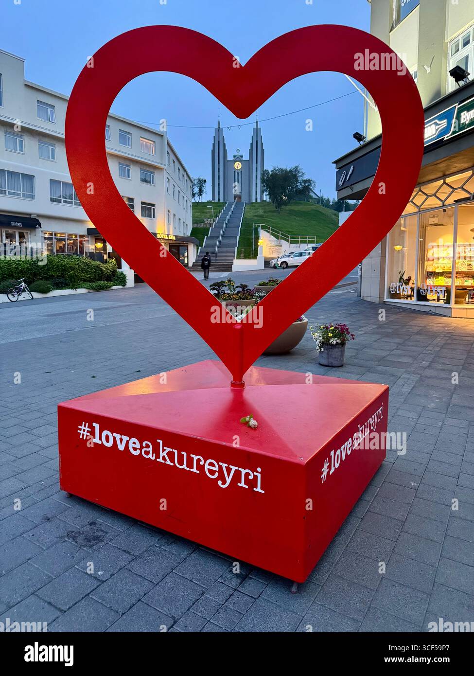 La creativa opera d'arte in metallo nel centro di Akureyri incornicia la storica Chiesa di Akureyri in una serata estiva. - Immagine stock catturata con smartphone