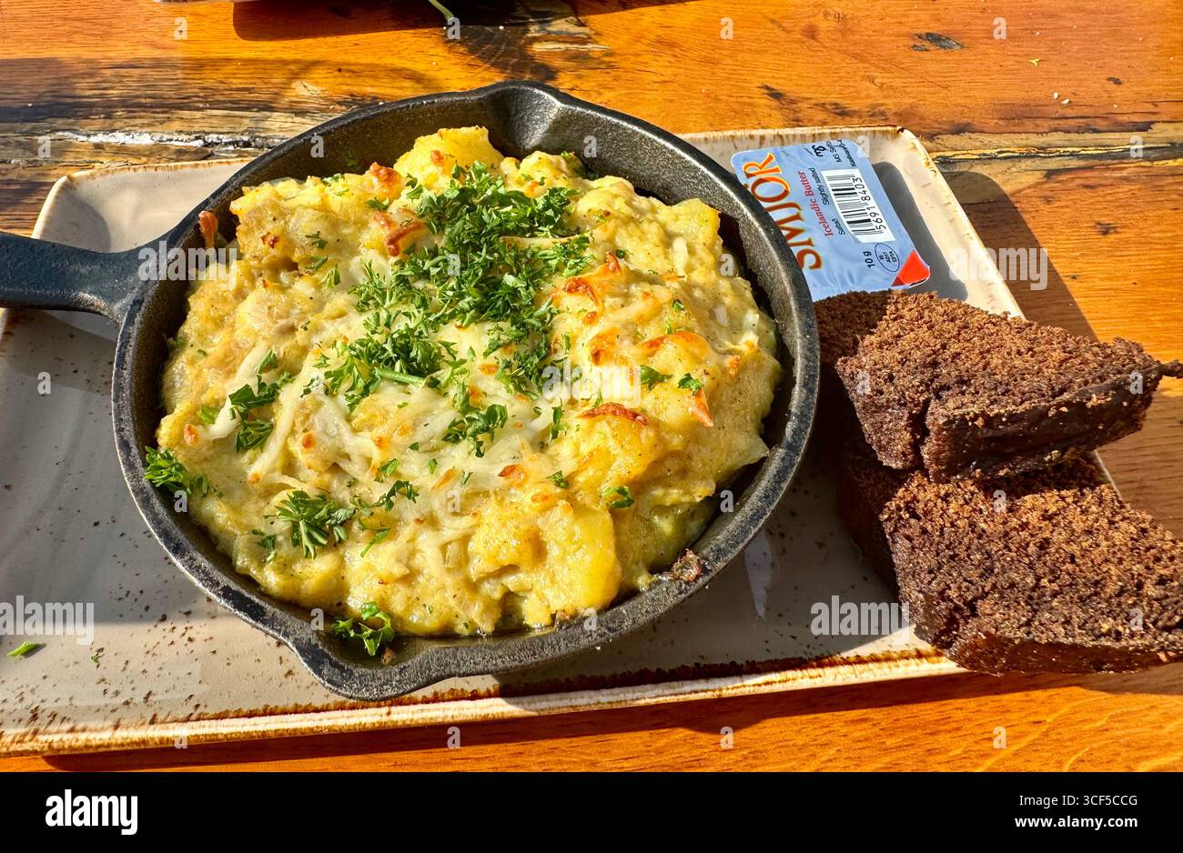 Delizioso pasto islandese tradizionale a base di stufato di pesce servito in una piccola padella di ghisa insieme alla lettura di segale fatta in casa. - Immagine stock catturata con smartphone