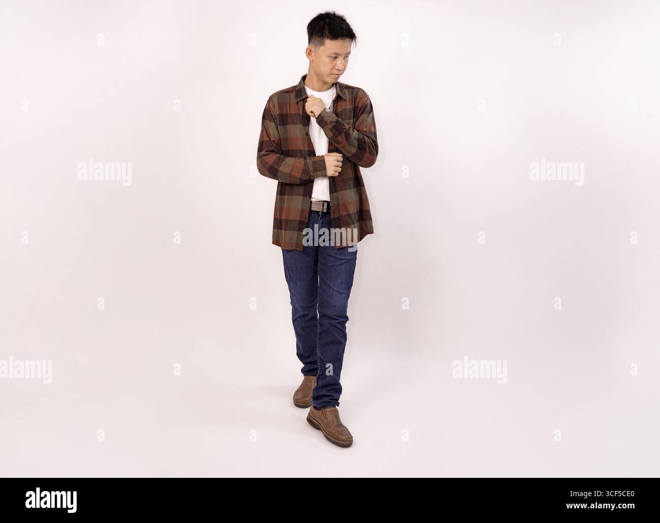 un giovane casual con una camicia a quadri e jeans rivolti verso l'esterno Foto Stock