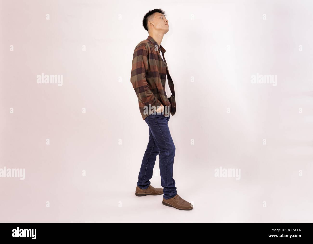 un giovane casual con una camicia a quadri e jeans rivolti verso l'esterno Foto Stock