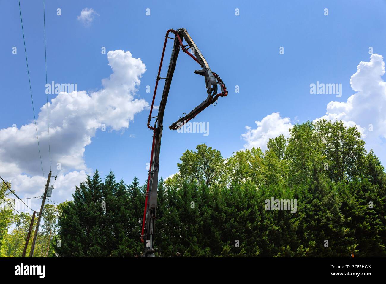 Il veicolo per costruzioni miste solleva la pompa per calcestruzzo in alto per versare cemento bagnato in lavori di costruzione diurna Foto Stock