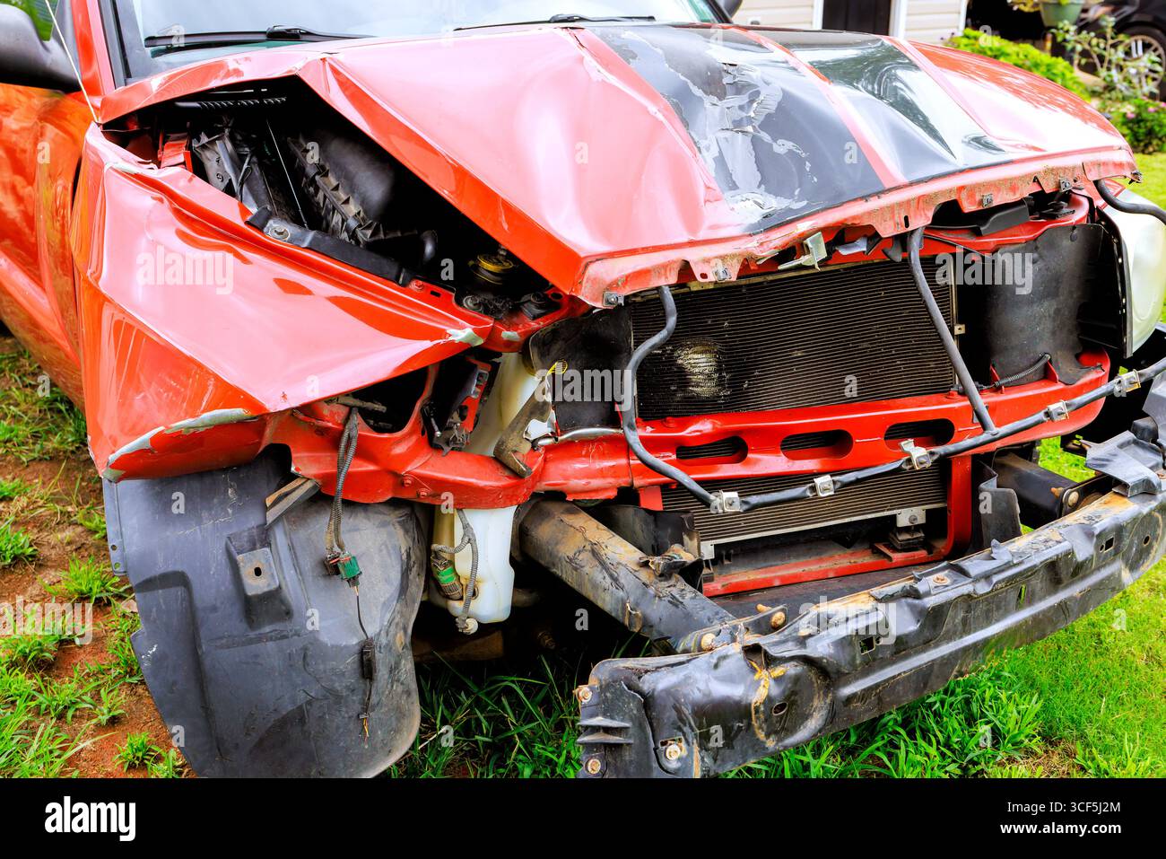 Il pick-up rosso mostra gravi danni alla parte anteriore dopo una collisione con paraurti danneggiato, componenti esposti. Foto Stock