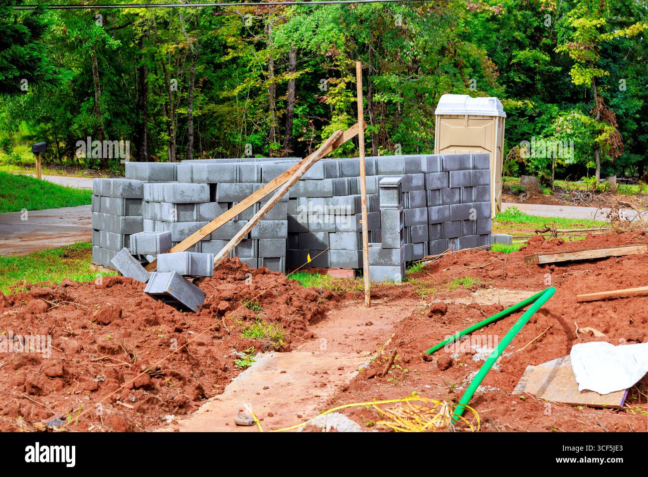 Gli uomini lavorano sulla costruzione di pareti in pietra utilizzando blocchi di cenere in un quartiere periferico circondato da un'area di costruzione Foto Stock