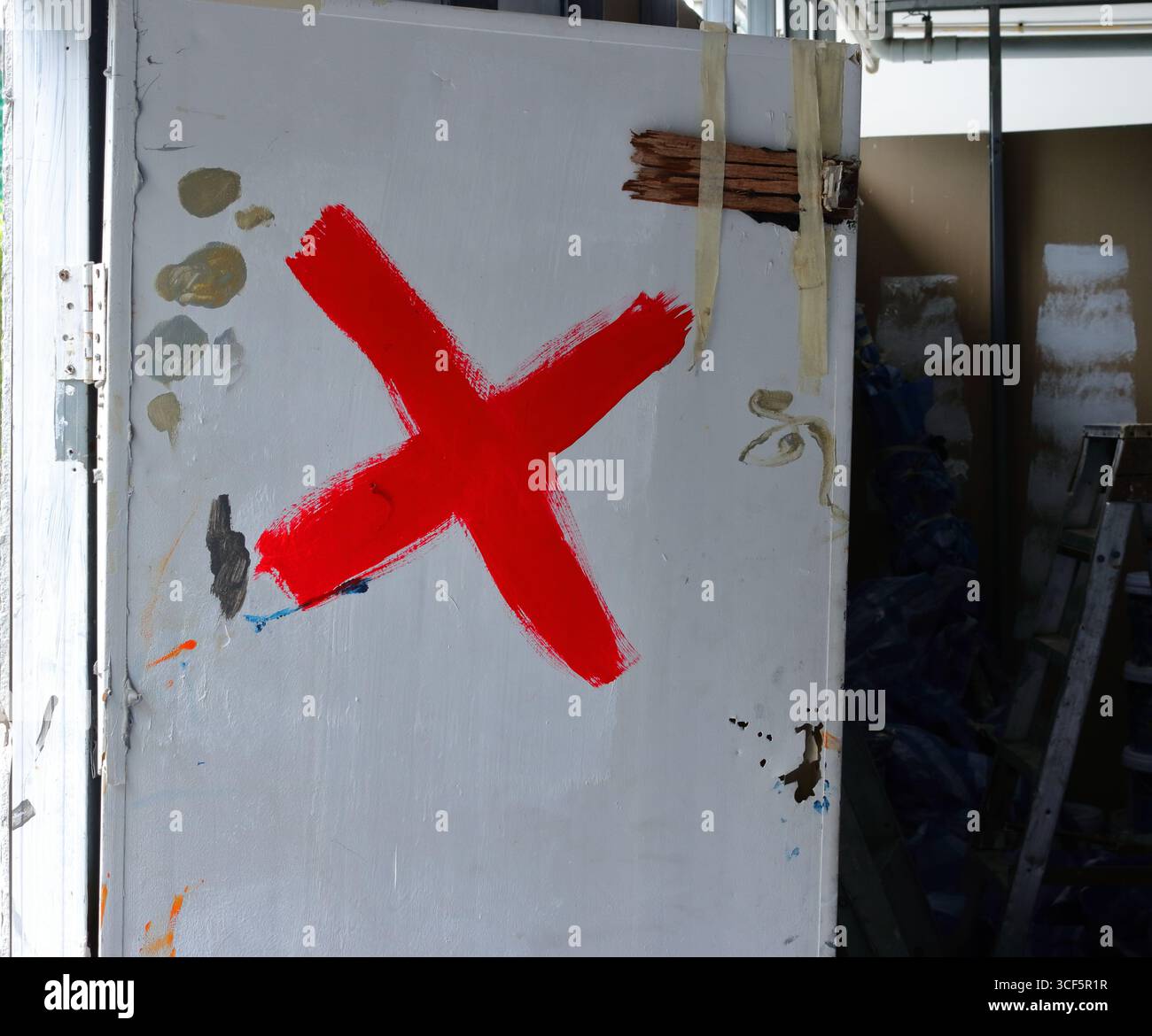 Contrassegno X dipinto di colore rosso su porta di legno bianca di un magazzino Foto Stock