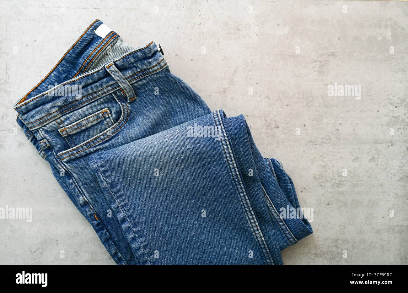 Jeans classici blu ripiegati sulla scrivania con spazio per un'idea perfetta come un modello piatto Foto Stock