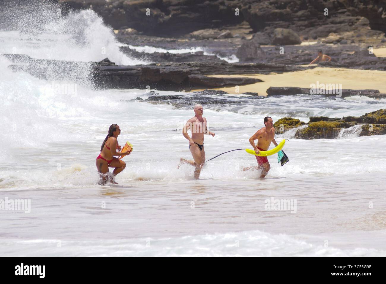I bagnini si precipitano nel surf per salvare l'uomo in difficoltà al Sandy Beach Park di Honolulu, un momento urgente di coraggio e precisione sul bordo dell'oceano. Foto Stock