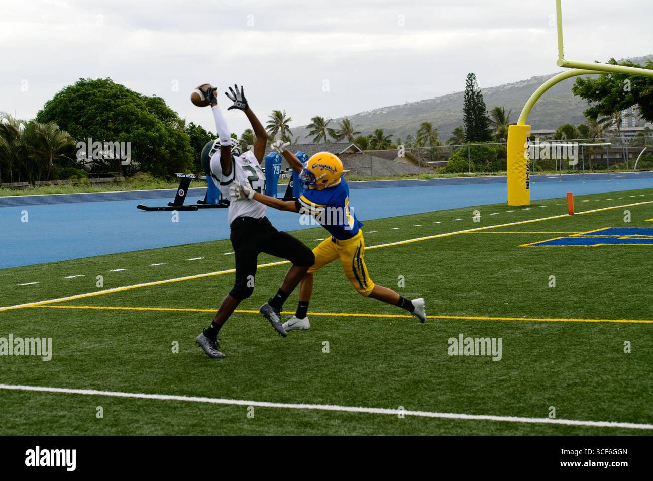Il wide receiver dell'Aiea fa cadere un passaggio da touchdown critico sotto la forte pressione di un difensore del Kaiser in questa resa dei conti del football delle scuole superiori. Foto Stock