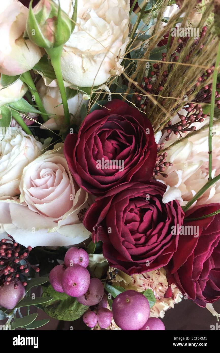Romantico bouquet floreale con rose rosse rose rosa petali delicati e frutti di bosco esposti con foglie verdi fotografati in Lombardia Italia Foto Stock