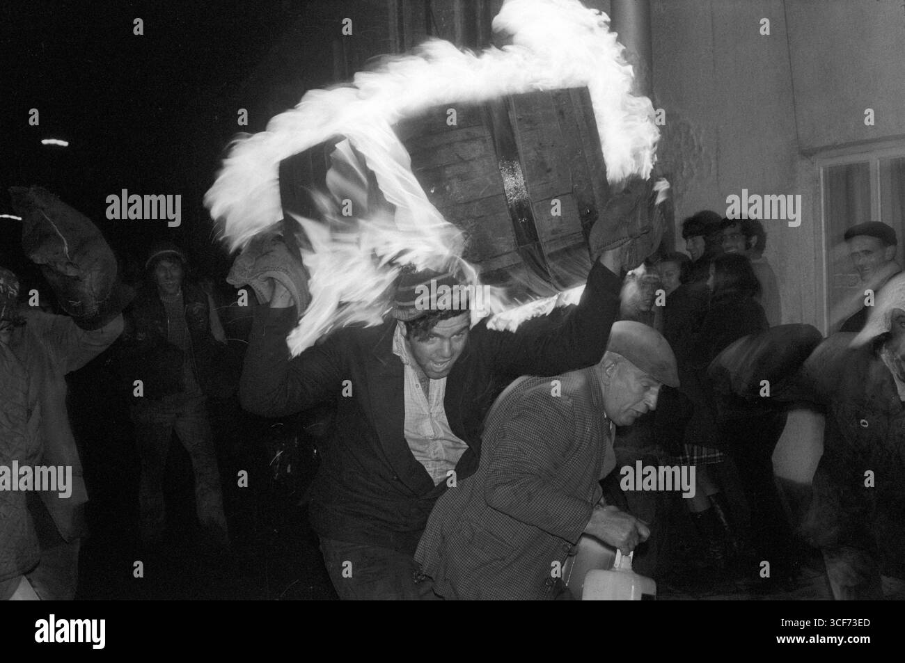Tar Barrel Rolling, Ottery St Mary, Devon. Un uomo corre per la strada di Ottery St Mary con una botte di catrame fiammeggiante che gli brucia sulle spalle. Inghilterra 5 novembre 1973 1970s Regno Unito HOMER SYKES. Foto Stock