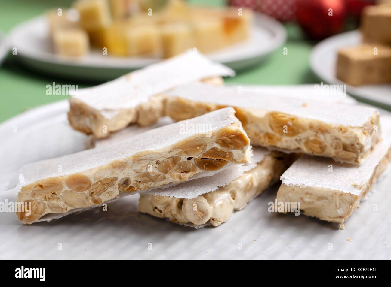 Primo piano di un piatto con turrone duro o turrone di Alicante, servito su un tavolo di Natale. Un dolce tradizionale spagnolo Foto Stock