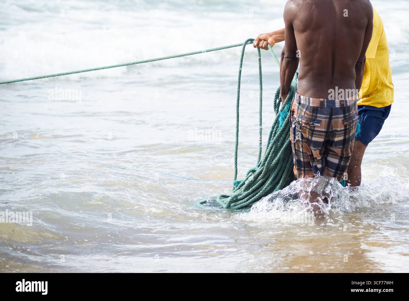 Mezzo corpo di pescatori non identificati che raccolgono la rete da pesca dopo la cattura del pesce. Pesce, pesca come hobby. Brasile Foto Stock