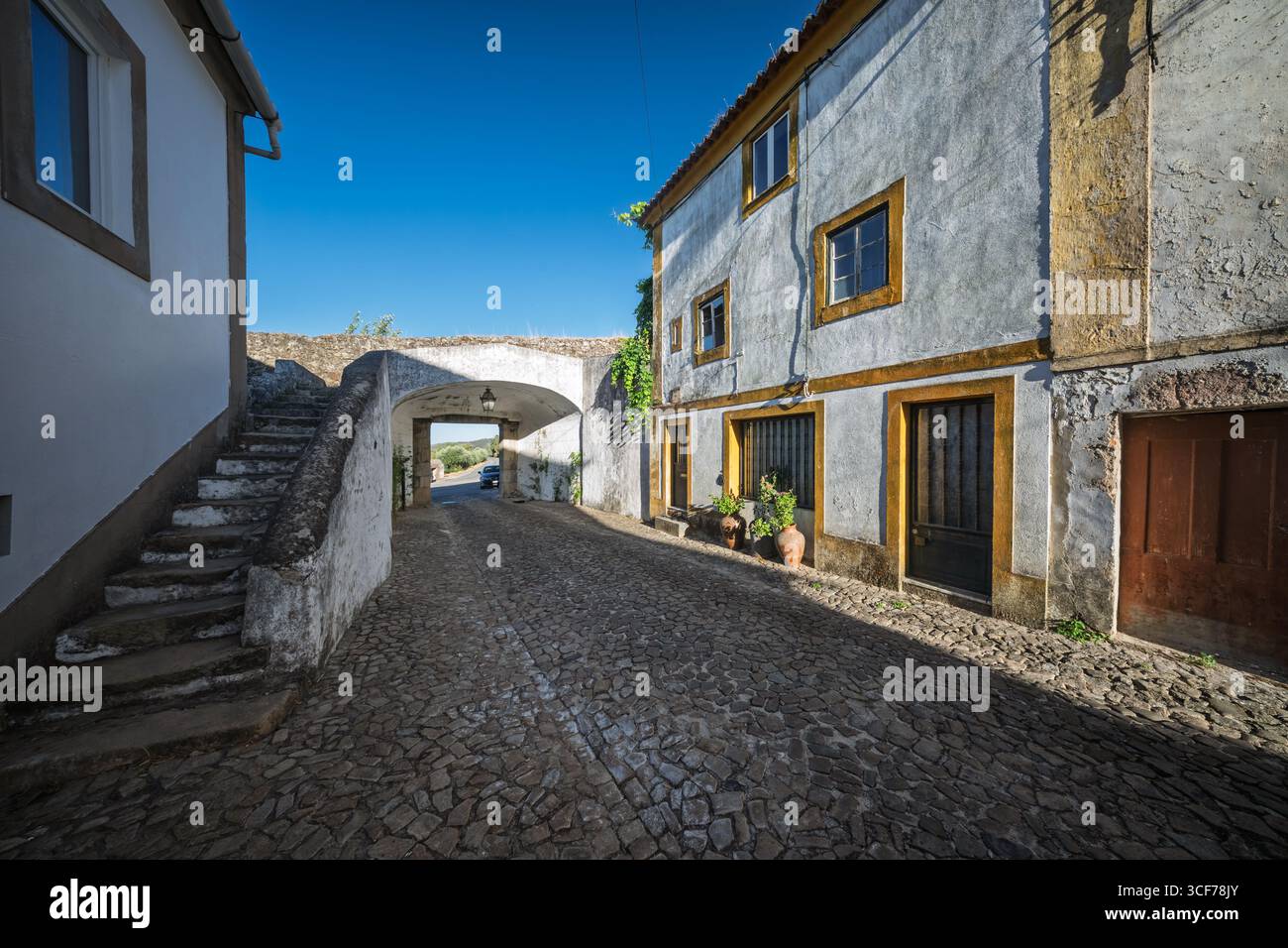 La soleggiata strada acciottolata di Rua de Santo Amaro conduce alla storica porta de Santa Catarina a Castelo de vide, Alentejo. Foto Stock