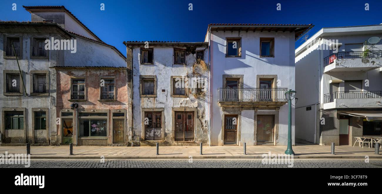 Le pareti incrinate con viti si stagliano accanto a vernice fresca e pietra lucida a Braganza, mettendo in risalto il carattere e la resilienza della città. Foto Stock