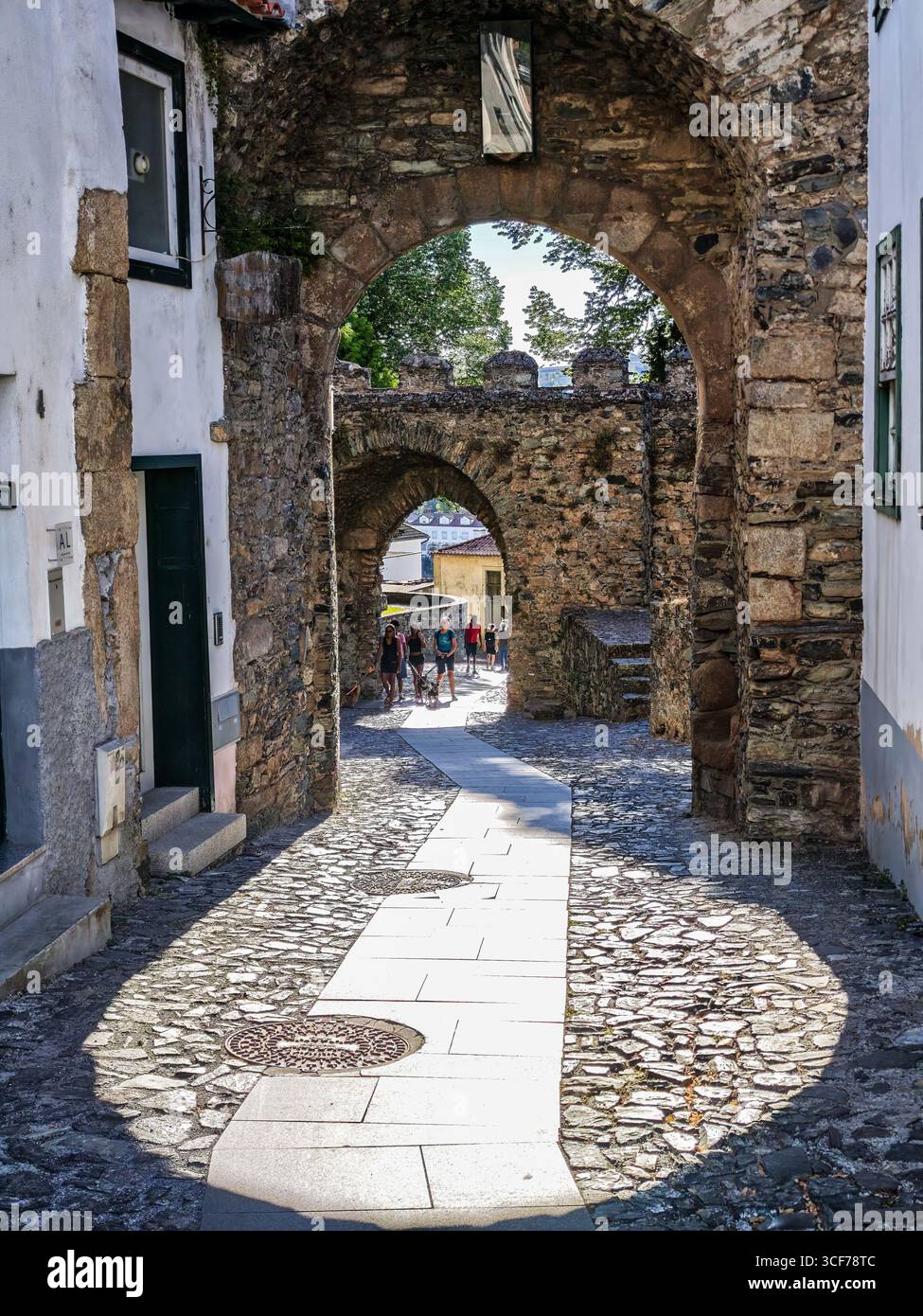 Braganza, Portogallo, 21 luglio 2025, i visitatori camminano attraverso gli archi in pietra del castello di Braganza al tramonto, con una luce dorata che getta incantevoli ombre. Foto Stock
