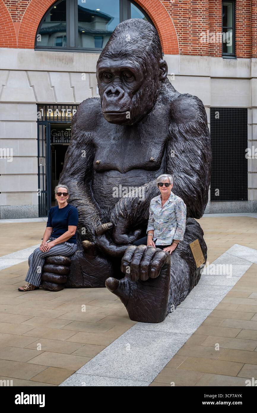 Due femmine sedute sulle gambe di una grande scultura in bronzo di un gorilla, come parte dell'installazione Wild About Babies degli artisti Gillie e Marc. Foto Stock