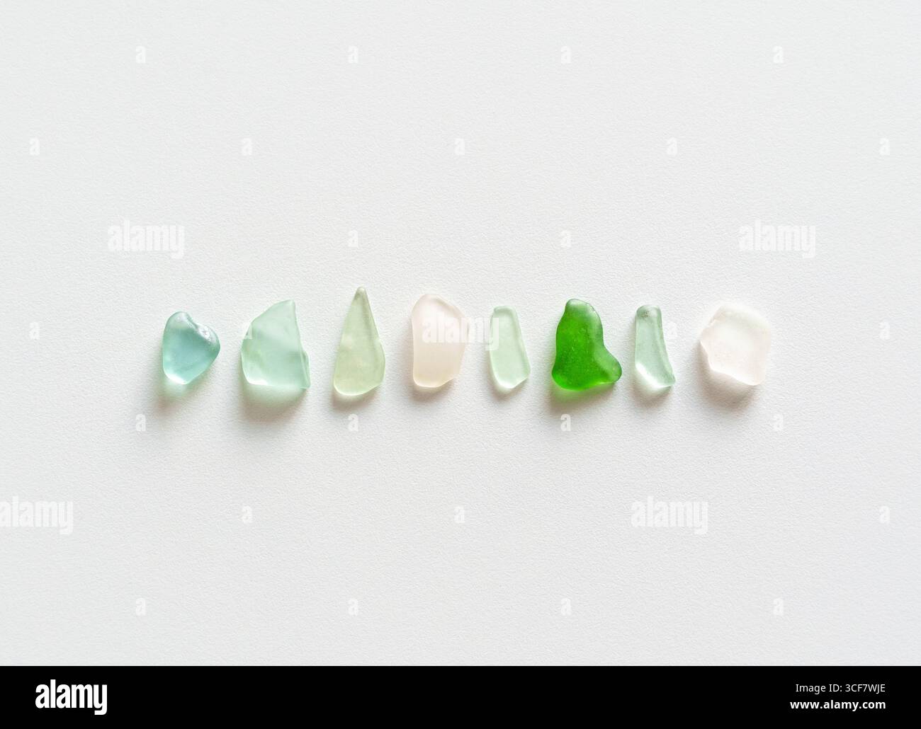 Disposizione minimalista di colorati pezzi di vetro marino su sfondo bianco Foto Stock