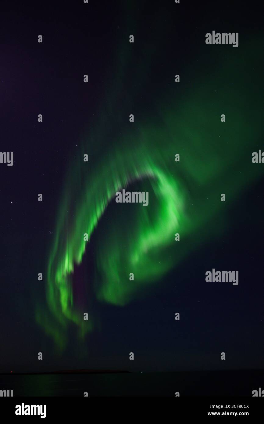 Spirale verde di aurora che si muove nel cielo notturno, Islanda Foto Stock