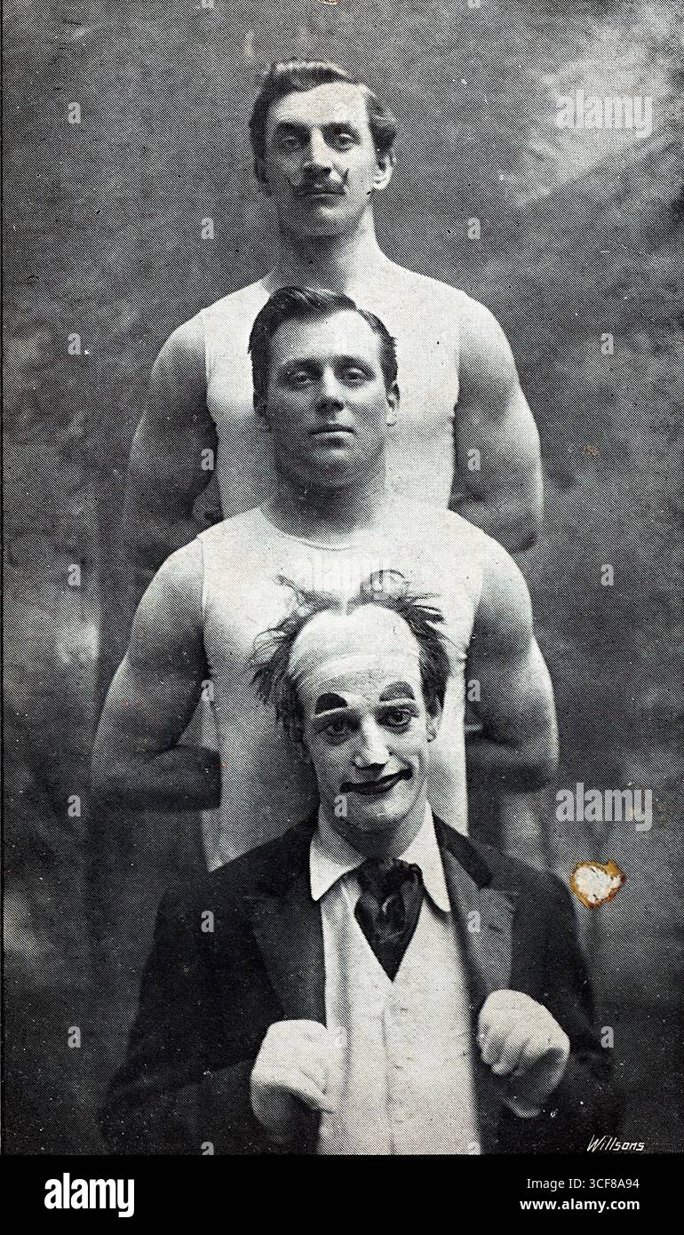 Questa cartolina del 1912, fotografata da Willsons e posttimbrata dopo una performance Weston-Super-Mare, presenta l'Hermes Trio, acrobati erculesi catturati in una suggestiva posa verticale. Davanti, un clown teatrale con facciate bianche e mani rialzate aggiunge stravaganza, mentre due uomini muscolosi stanno dietro in camicie senza maniche, braccia piegate, espressioni composte. La giustapposizione di personaggi comici e di forza evoca il fascino del vaudeville e lo spettacolo edoardiano. Lo sfondo sfocato e la composizione nitida sottolineano l'impatto visivo e l'identità delle prestazioni del trio nell'intrattenimento dei primi anni del XX secolo. Foto Stock