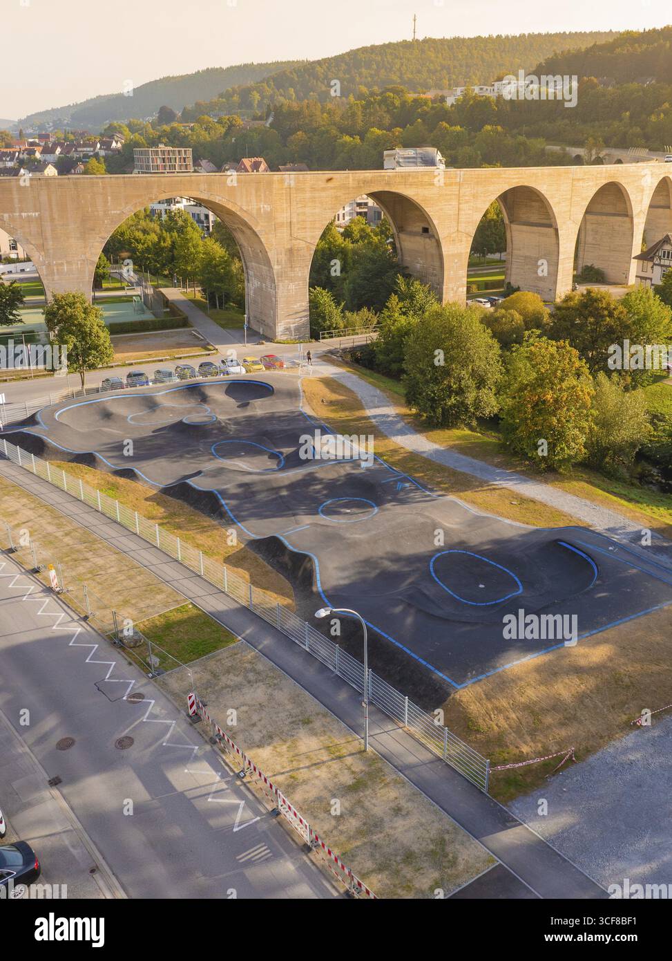 PUMP Track accanto a un imponente viadotto, circondato da alberi e paesaggio urbano, Nagold PUMP Track, quartiere Calw, Germania Foto Stock