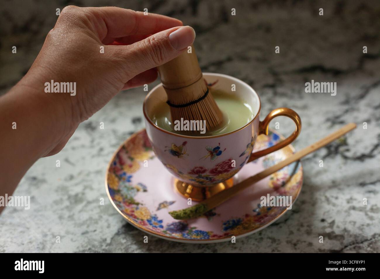 Mescolare un tè matcha con una frusta di bambù Foto Stock