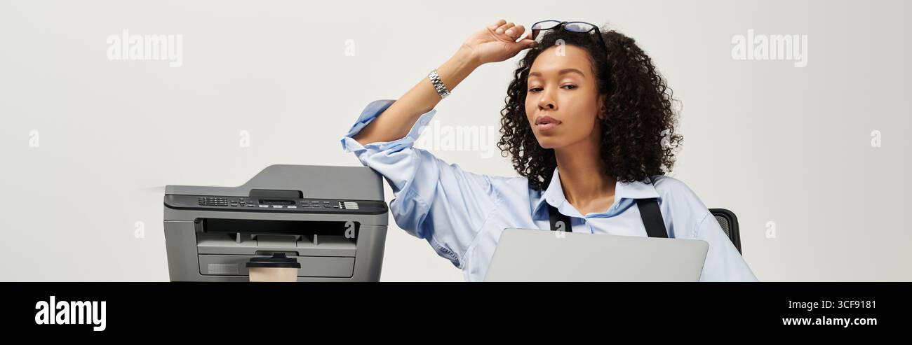 Giovane donna elegante impegnata in un lavoro attento utilizzando moderne attrezzature per ufficio. Foto Stock