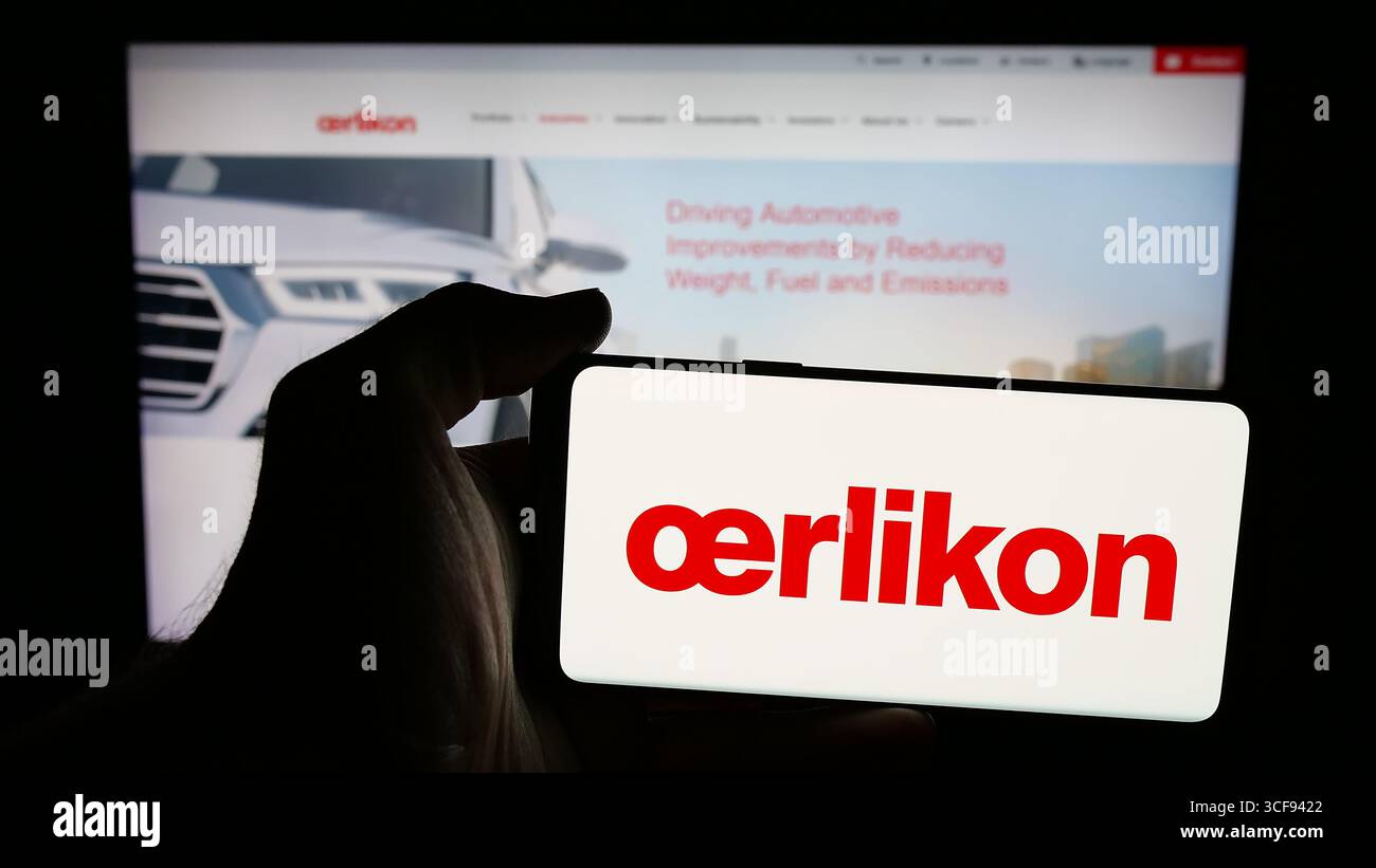 Stoccarda, Germania - 20-08-2025: Persona che detiene un cellulare con il logo della società svizzera OC Oerlikon Corporation AG sullo schermo davanti alla pagina web. Foto Stock
