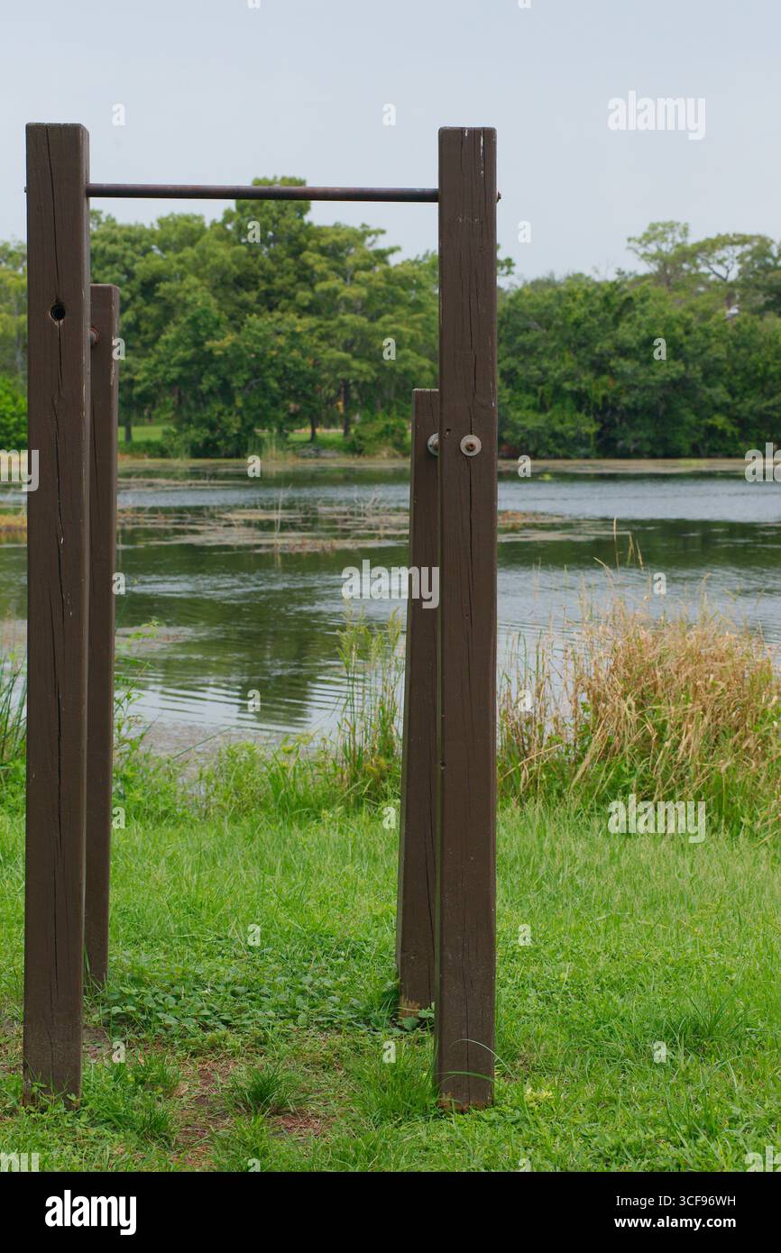 Bar esterno in legno vicino al lago panoramico e alla prateria in un parco. Il robusto bar estraibile in legno si erge tra una vibrante erba verde e un calmo lungolago Foto Stock