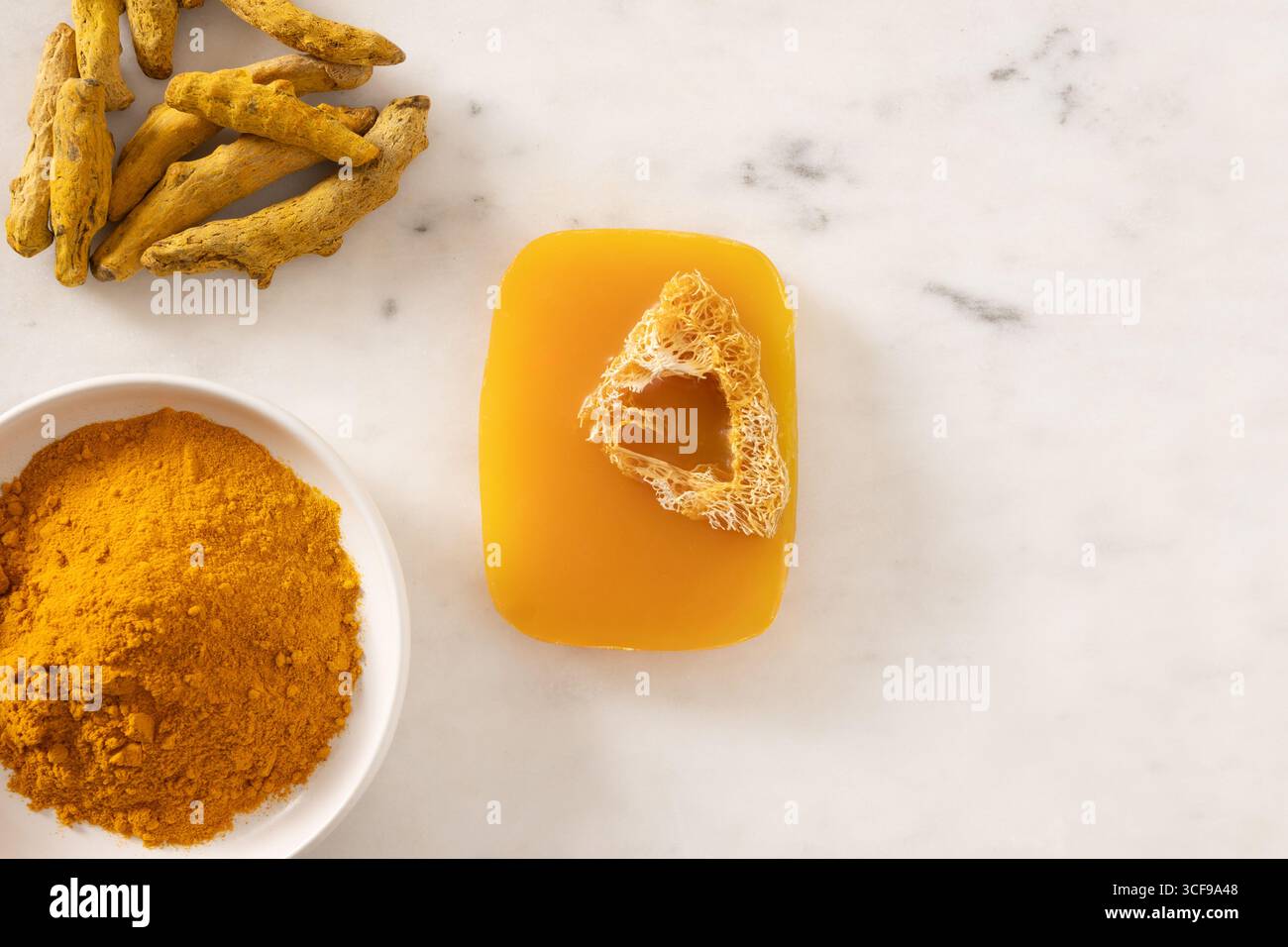 Sapone curcuma e radice di curcuma in polvere su sfondo bianco marmo. Prodotto per la cura della pelle biologico perfetto per il benessere, la bellezza e la cura organica del corpo Foto Stock