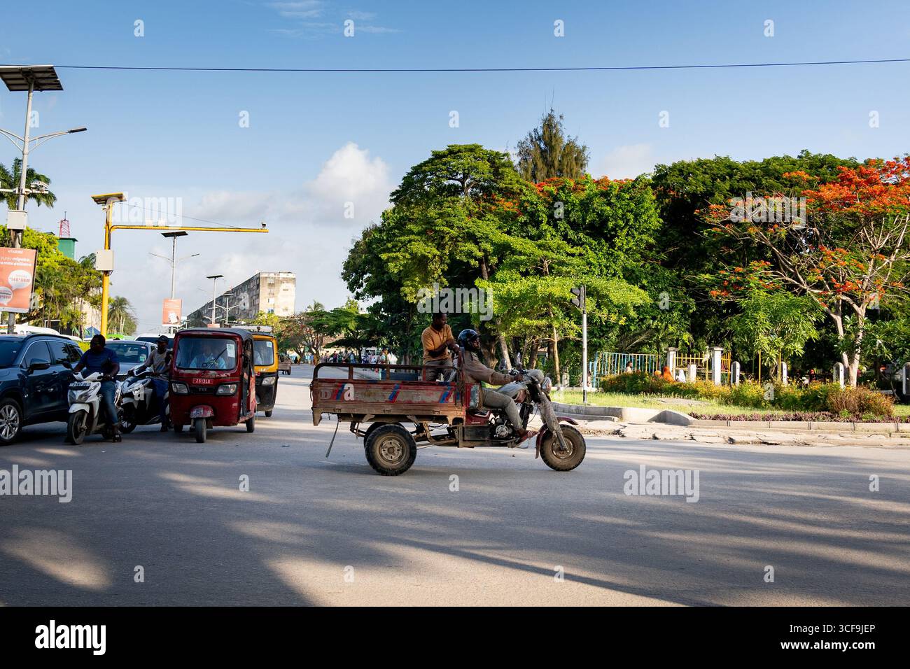 Traffico stradale con motociclette e tuk tuk a Zanzibar, Tanzania Foto Stock