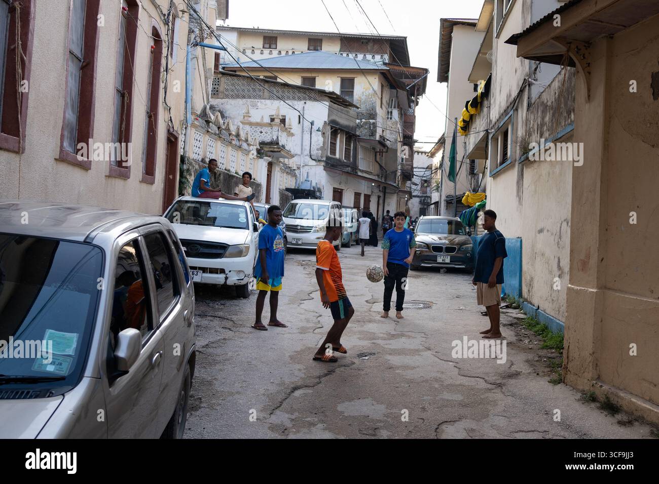 I bambini giocano a calcio nelle strade di Stone Town, Zanzibar Foto Stock